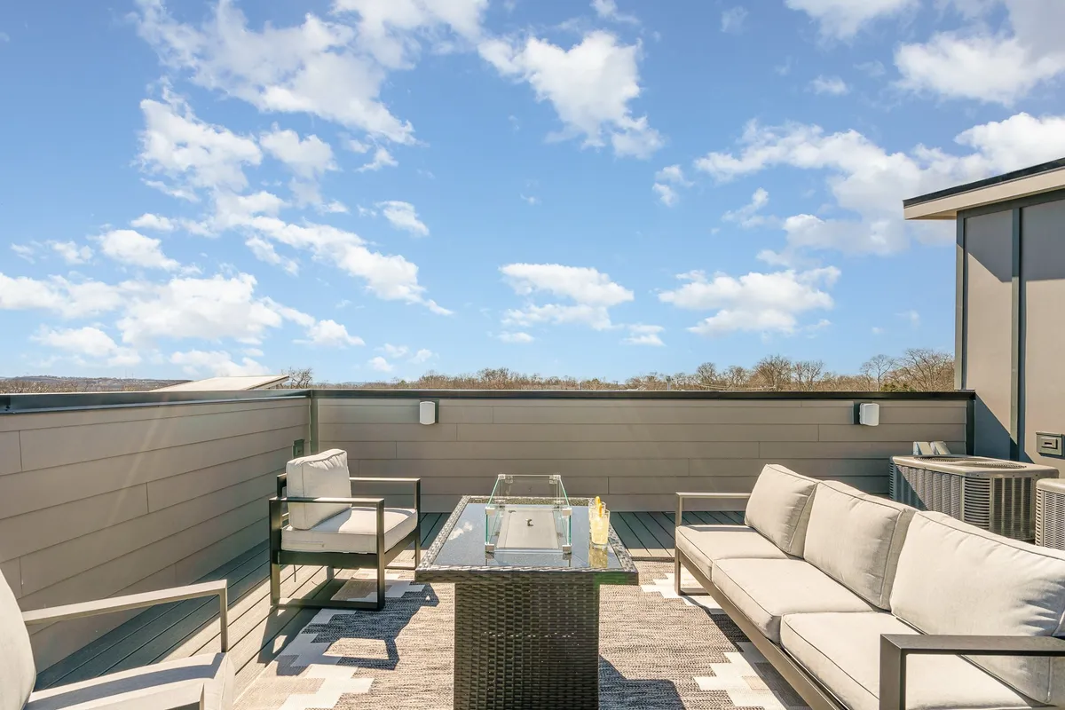 An inviting outdoor seating area featuring a fire table, with expansive views of the sky and city. The space is designed for group socialization, making it perfect for evening gatherings or casual meetings under the stars.
