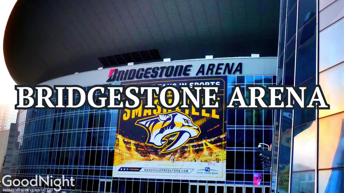 A dynamic exterior shot of the Bridgestone Arena, highlighting its iconic signage, Predators logo, and large event banners. The presence of crowds and the modern architecture evoke the excitement of attending concerts and sporting events in downtown Nashville.