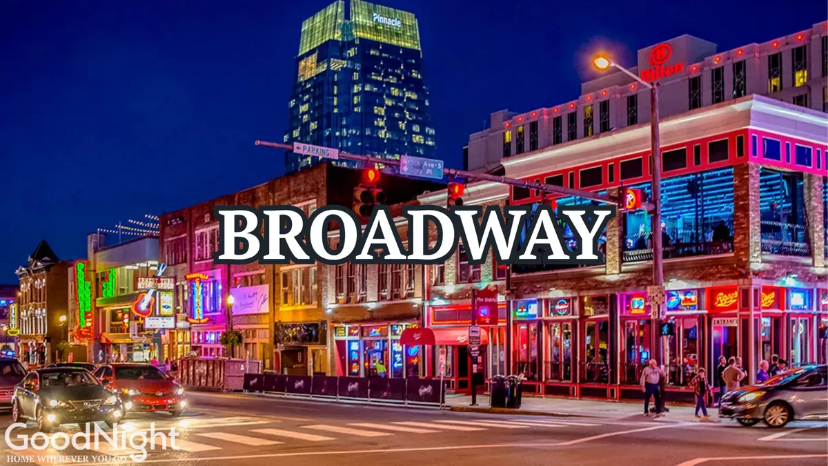 A vibrant Nashville street scene at night, filled with neon signs, busy crowds, and tall buildings. The energy of downtown is palpable, capturing the buzz of dining, live music, and nightlife along Broadway.